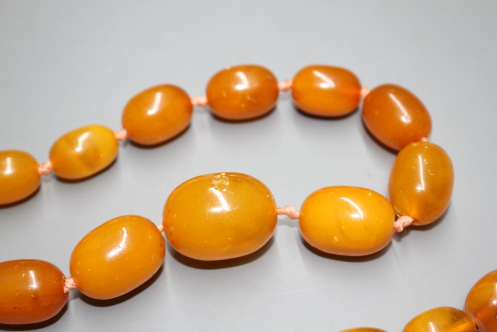 Two single strand graduated oval amber bead necklaces, with yellow metal clasps, one stamped 375,